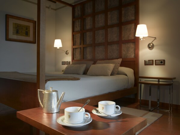 A hotel room with a bed, bedside lamps, a coffee table with a teapot and cups, and a framed picture on the wall. - Parador de Toledo (Toledo)
