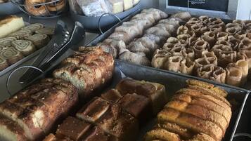 Een bakkerijdisplay met diverse gebakken producten, zoals brood, gebakjes en taarten.