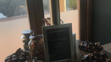 Ett bord med burkar fulla av honung och en menytavla med texten ”UNDESAYUNOS 7”, med utsikt över ett bergigt landskap genom stora fönster.