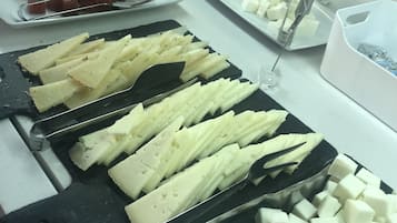 Buffet com diversas opções de queijos e frutas.