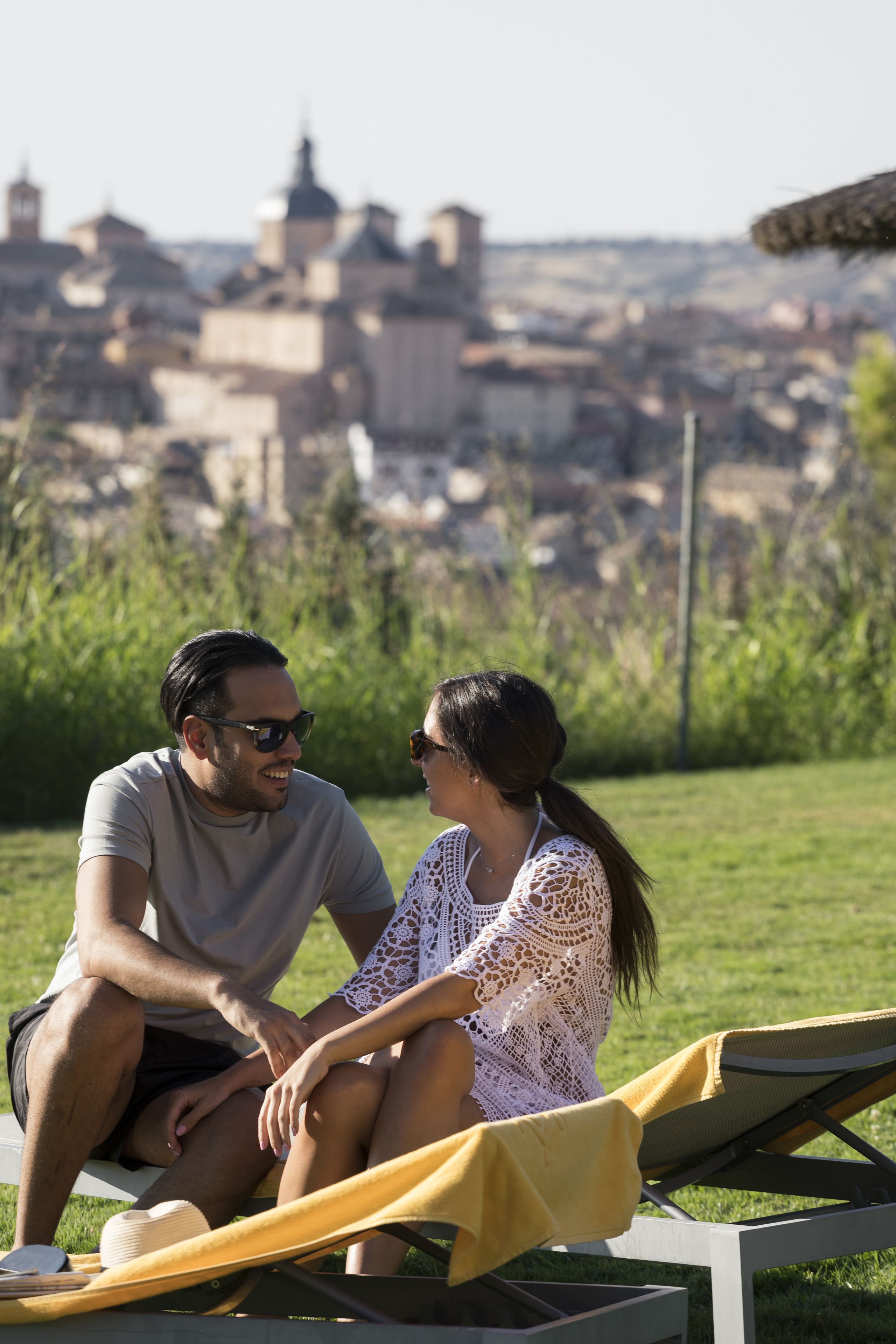 Una pareja sentada en un banco con un paisaje urbano al fondo.