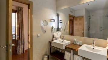 Une salle de bain moderne avec deux lavabos, un grand miroir et une douche.