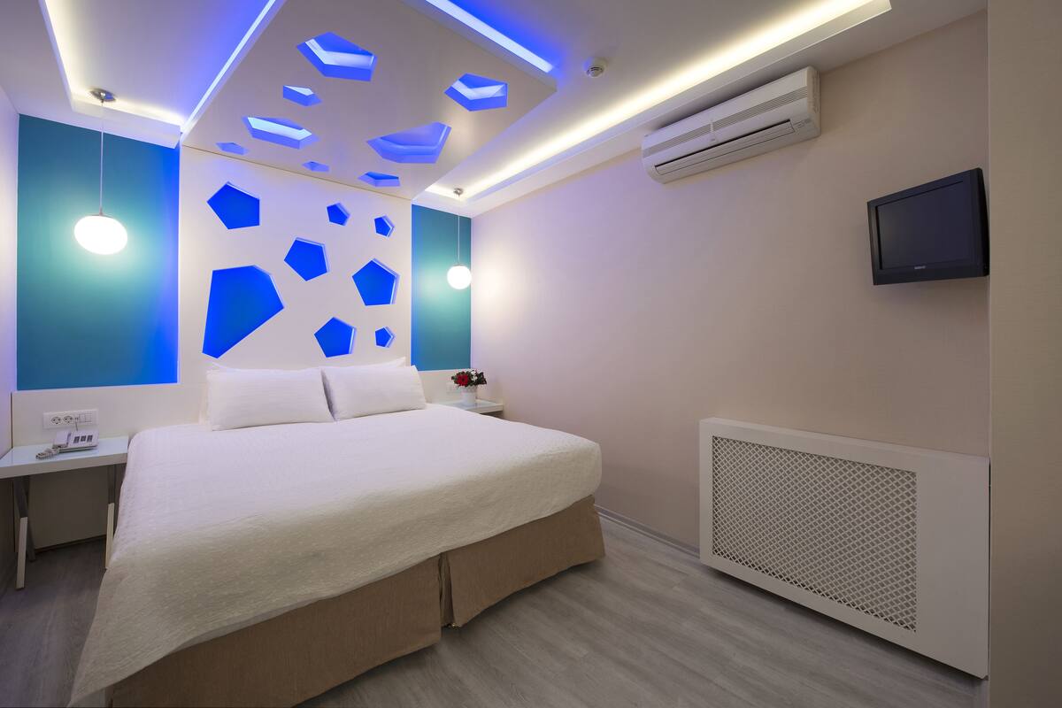 Una habitación de hotel moderna con cama, mesita de noche y televisor.