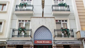 A hotel with multiple balconies, a central arched entrance, and outdoor seating.