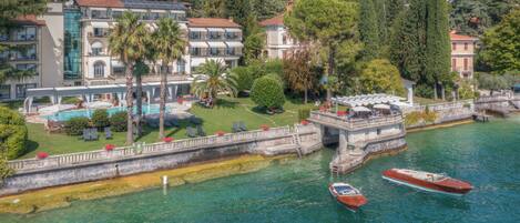A waterfront hotel with a pool, palm trees, and boats.