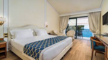 Ein Hotelzimmer mit Bett, Schreibtisch, Stuhl und einem Balkon mit Blick.