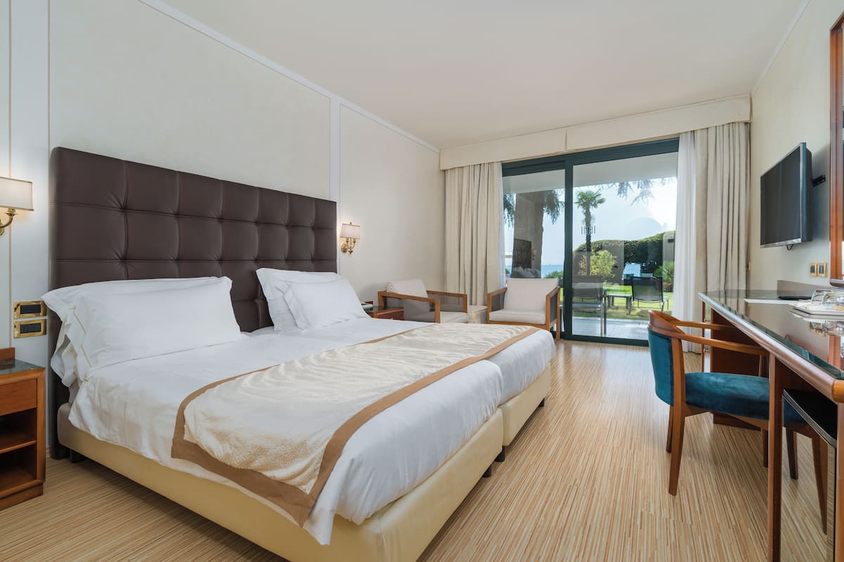 A hotel room with a large bed, a desk, a chair, and a TV.