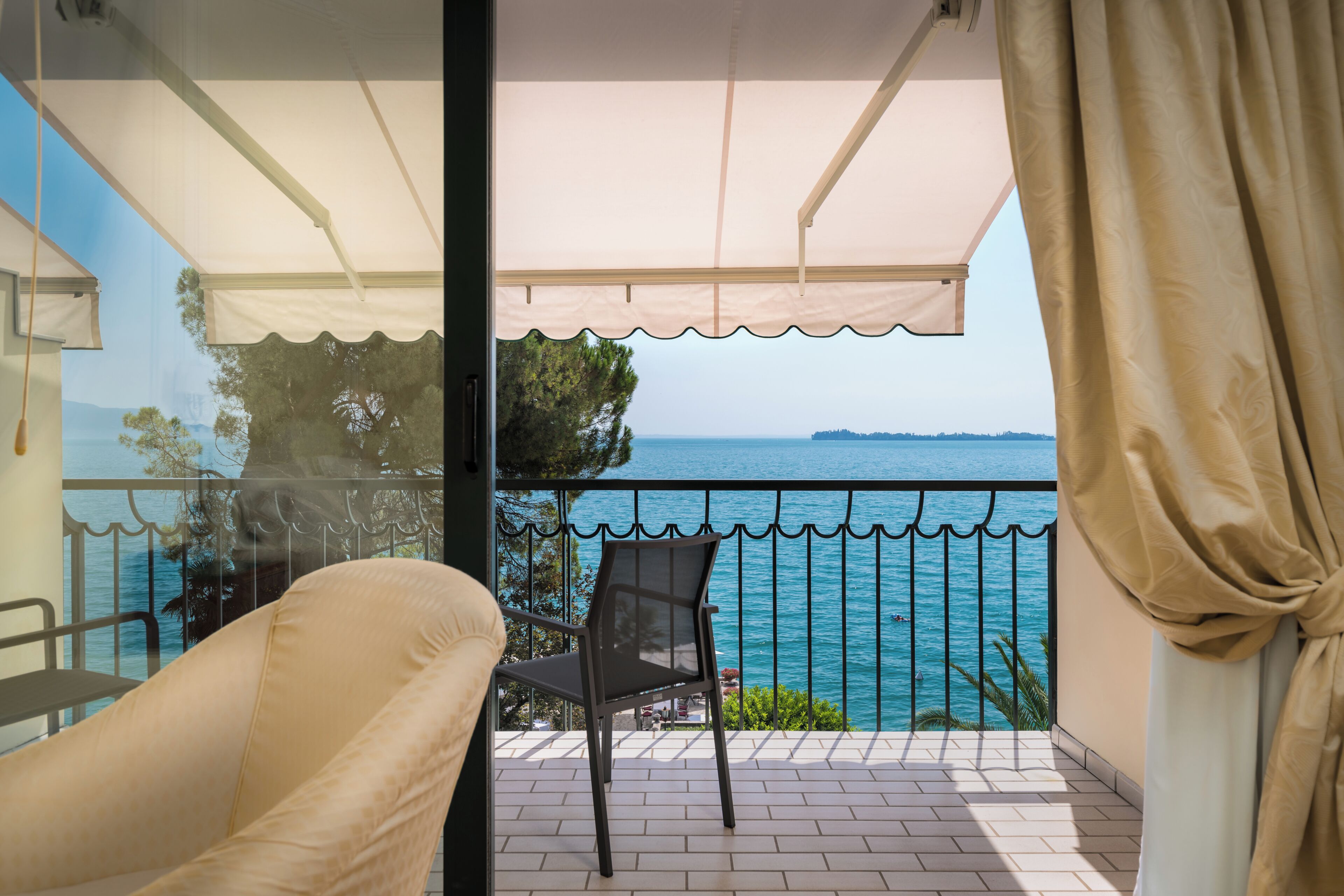 A balcony with a view of the sea, a chair, and a table.