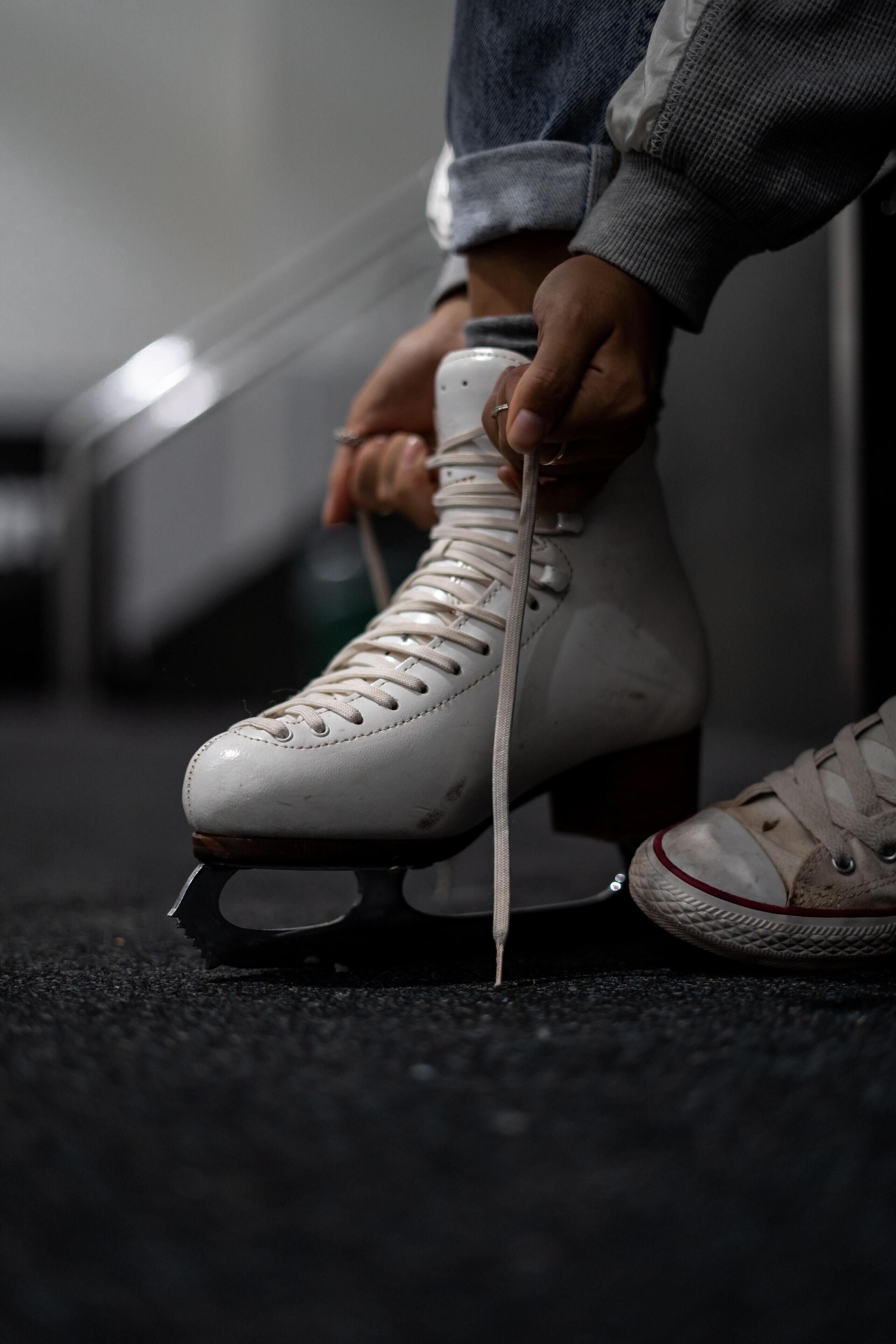 Un par de patines siendo atados sobre un piso alfombrado.