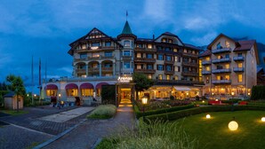 Een hotel met meerdere verdiepingen, een opvallende ingang, een terras en goed onderhouden tuinen.