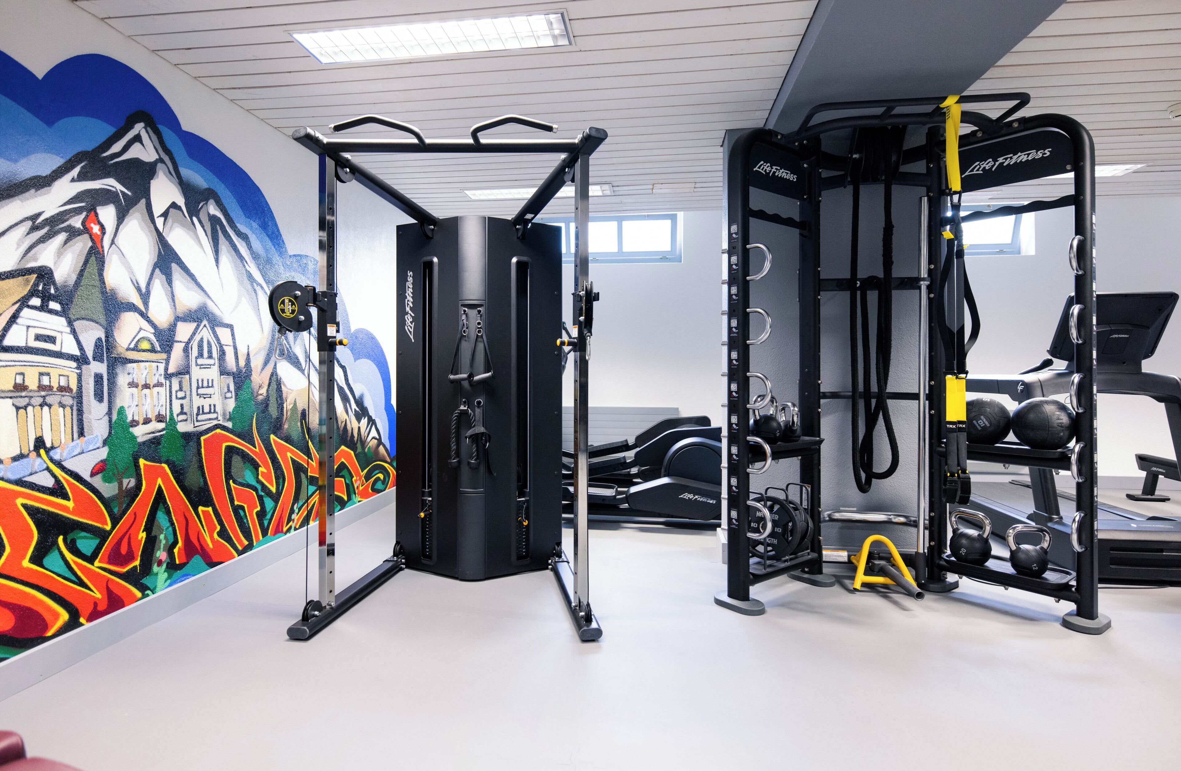 A gym with exercise equipment, a mural, and a window.