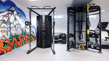 Une salle de sport équipée de matériel d’exercice, ornée d’une fresque murale et dotée d’une fenêtre.