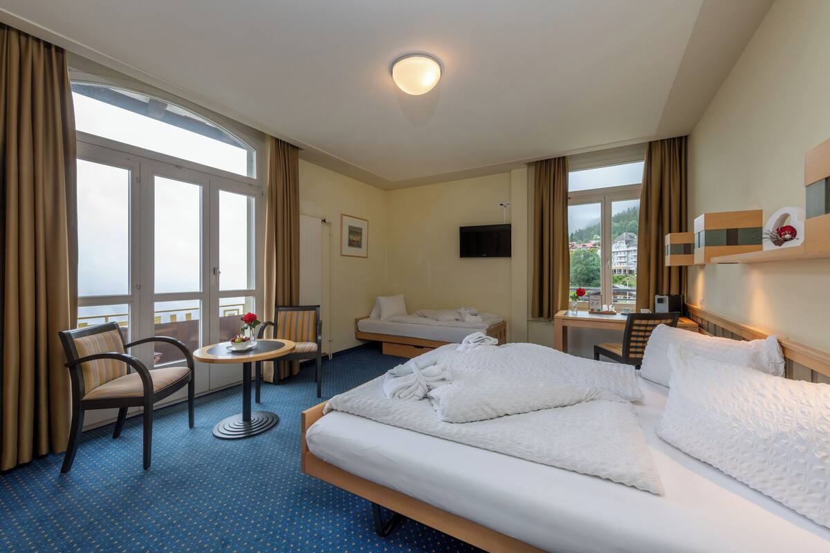 Ein Hotelzimmer mit Bett, Schreibtisch, Stuhl, kleinem Tisch und Fernseher.