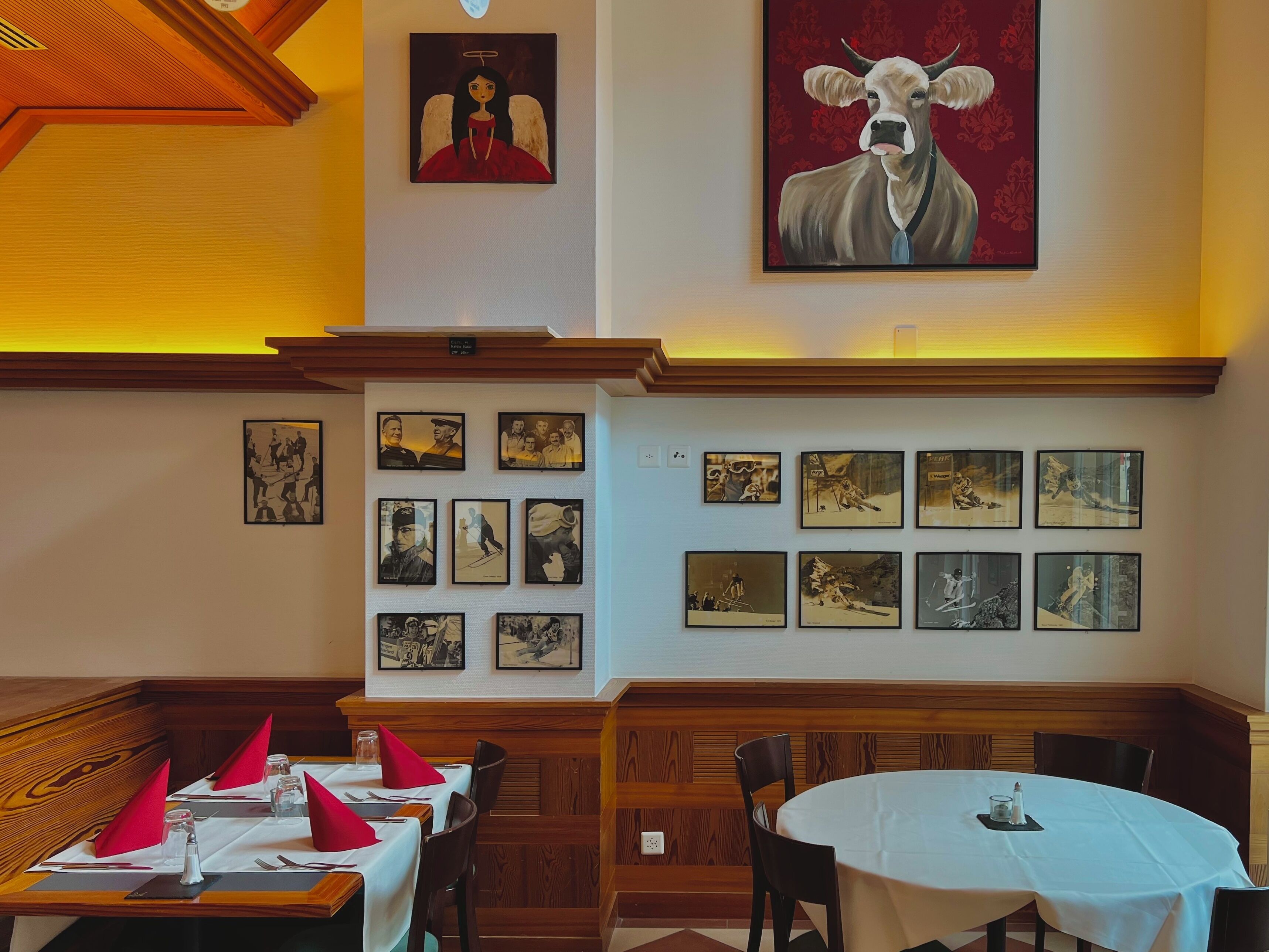 Ein Restaurant mit Holzwänden, hoher Decke und verschiedenen gerahmten Kunstwerken an den Wänden.