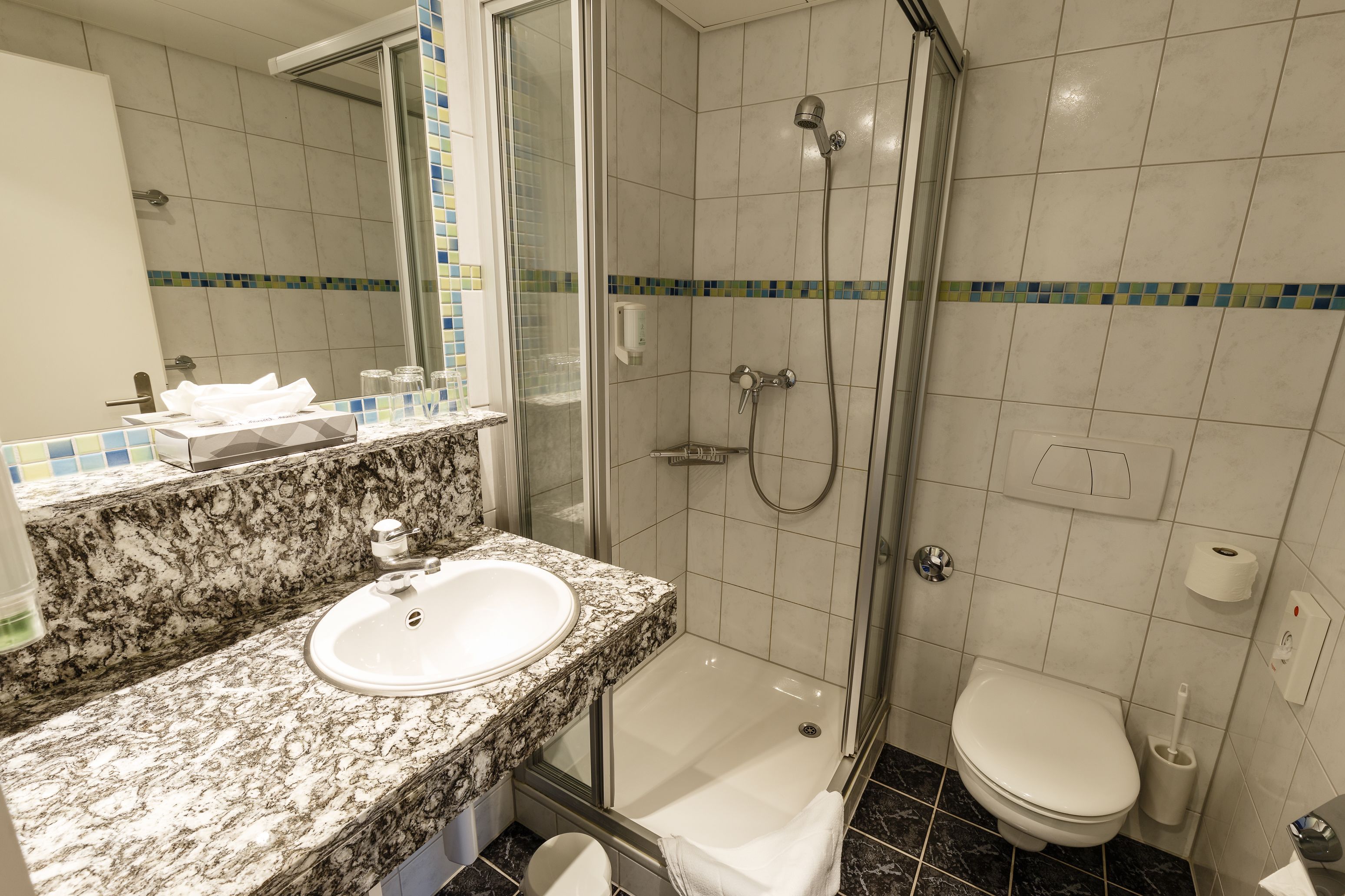 A bathroom with a sink, mirror, shower, and toilet.