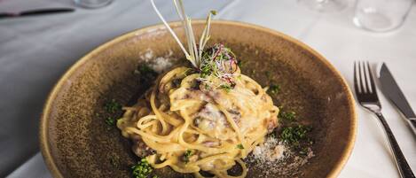 A plate of pasta with a garnish on a table.