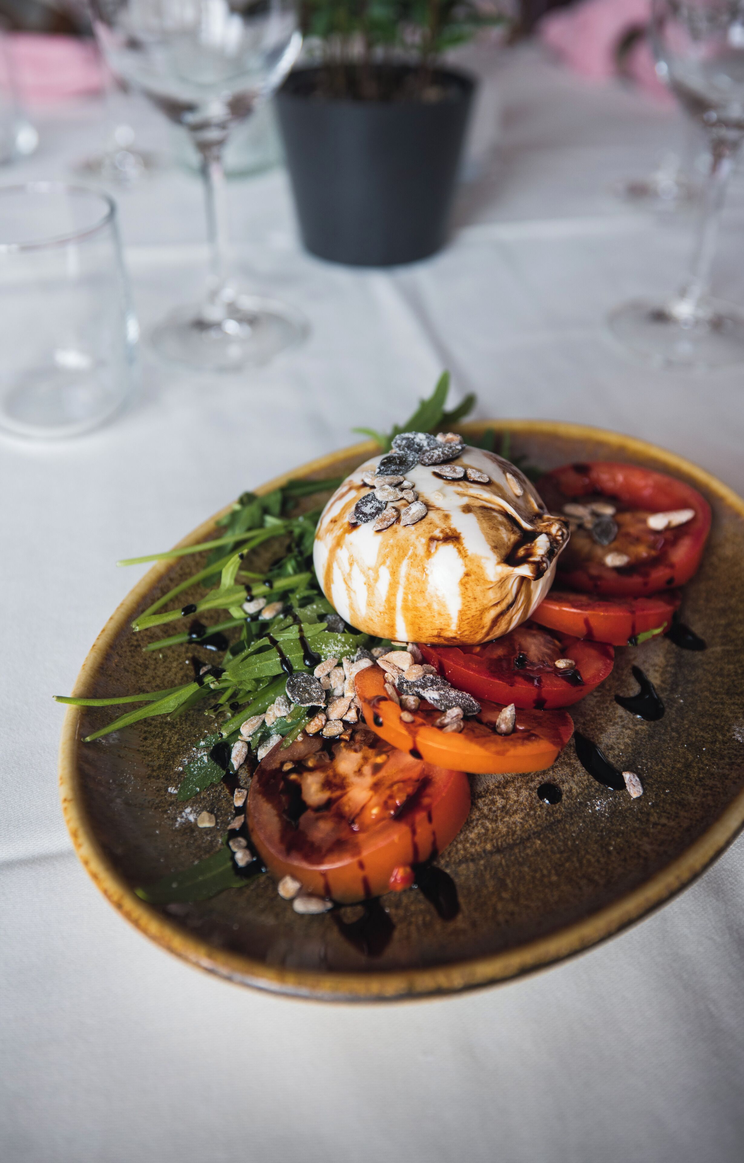 Une assiette contenant une salade, une tomate entière et un élément décoratif, le tout posé sur une table.