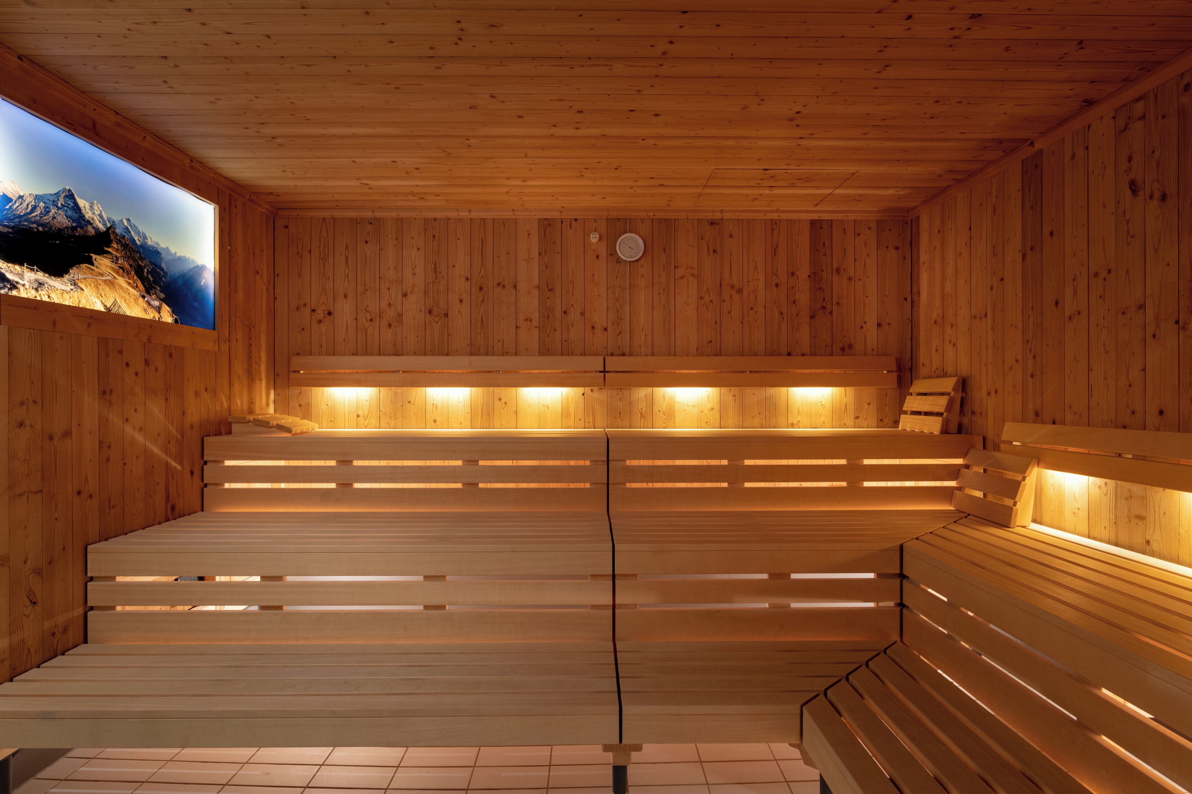 Een houten sauna met banken en uitzicht op bergen.