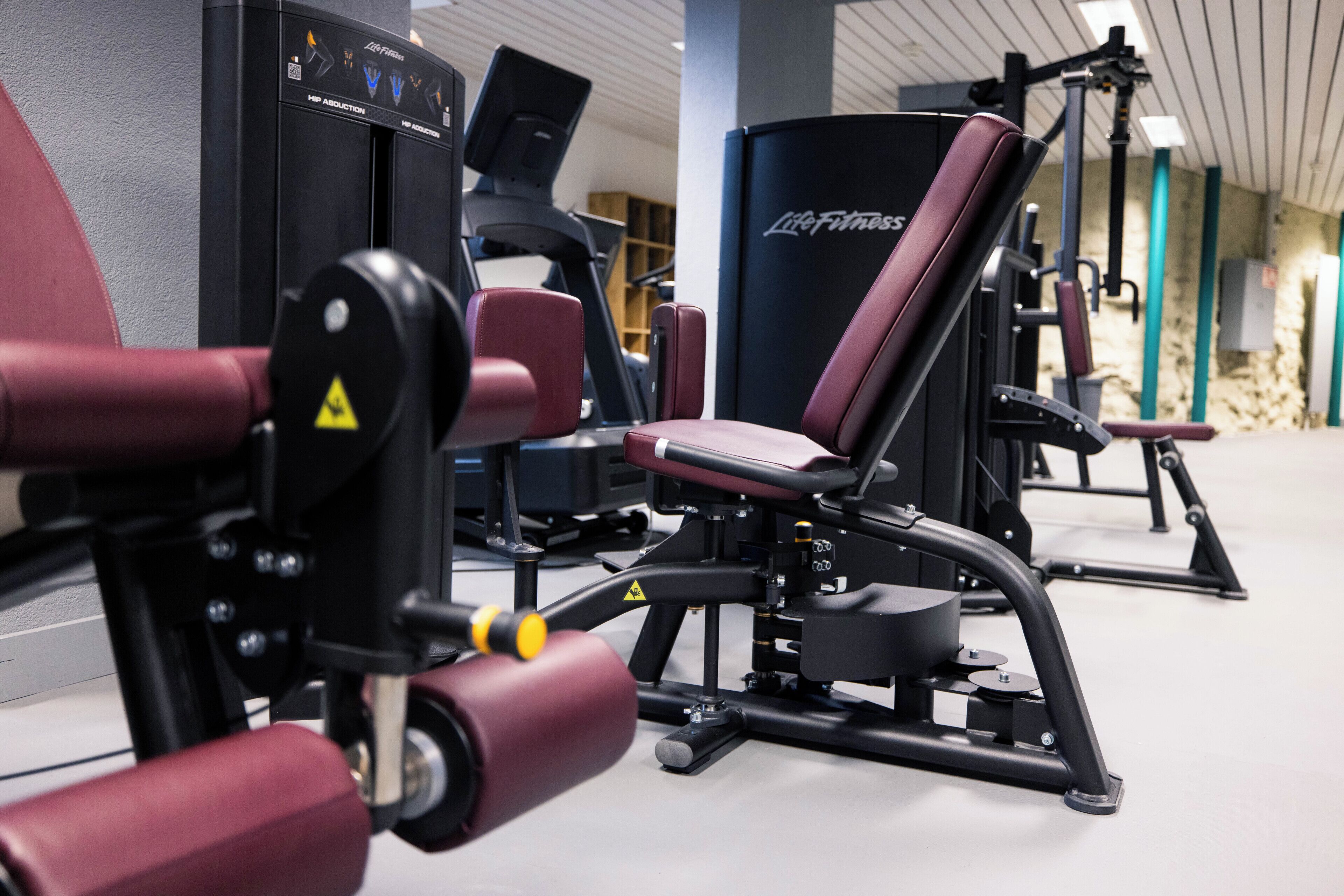 A gym with various exercise machines, including a leg press and a chest press.
