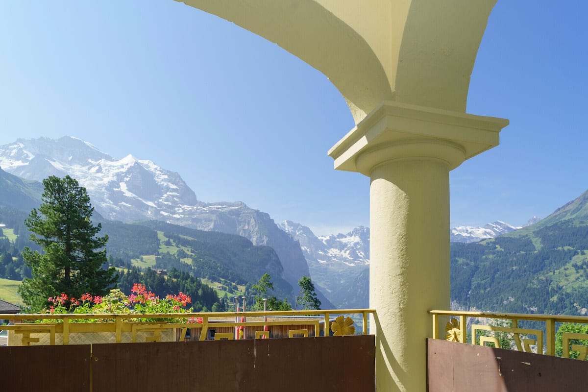 Ein Balkon mit Blick auf Berge, einem Holzzaun und einem gelben Geländer.