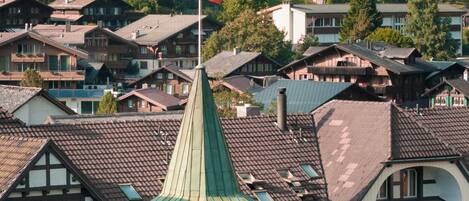 A traditional European town with chalet-style buildings, a prominent church tower, and a flag.