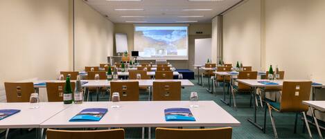 A conference room with multiple tables and chairs, equipped with water bottles and folders.