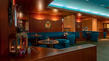 A modern lounge area with wooden paneling, blue seating, and ambient lighting.
