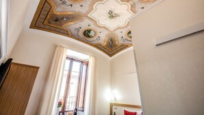 A room with a decorative ceiling, a window with curtains, and a wooden wardrobe. - Auditorium Mecenate (Rome)