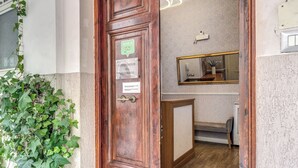 A wooden door with a sign indicating an auditorium, a mirror, and a bench in a room with a wooden floor. - Auditorium Mecenate (Rome)