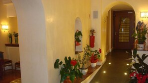 A hallway with a marble bench, potted plants, and a fire extinguisher on the wall. - Hotel Demetra Capitolina (Rome)