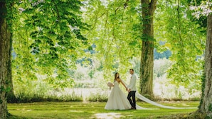 Un couple se trouve dans une zone boisée, entouré d’arbres et d’herbe.