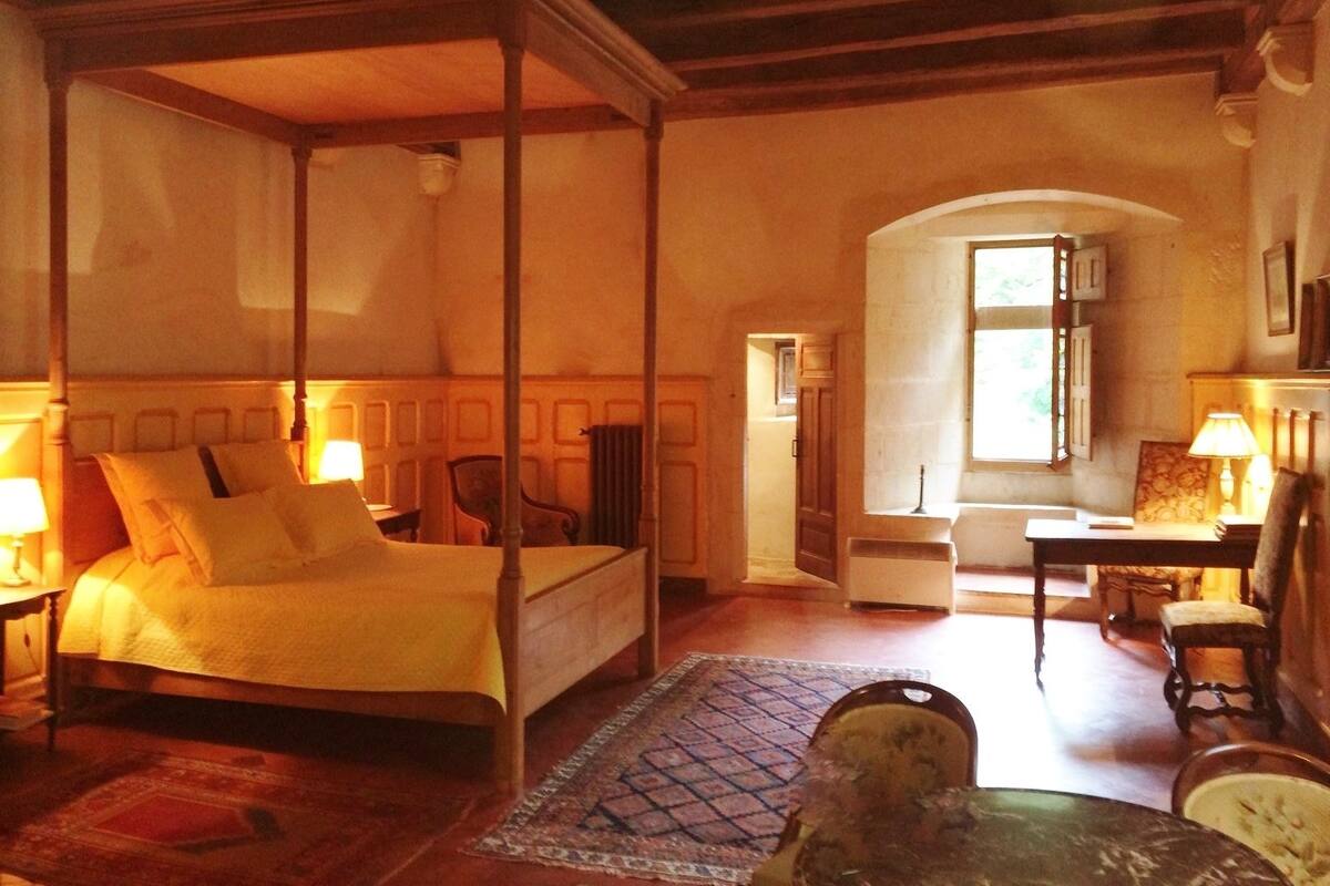 Een traditionele slaapkamer met een hemelbed, houten plafond en uitzicht op een gang.