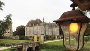 Un bâtiment historique surmonté d’un pont qui enjambe un canal, avec un lampadaire et un chemin menant à l’entrée.