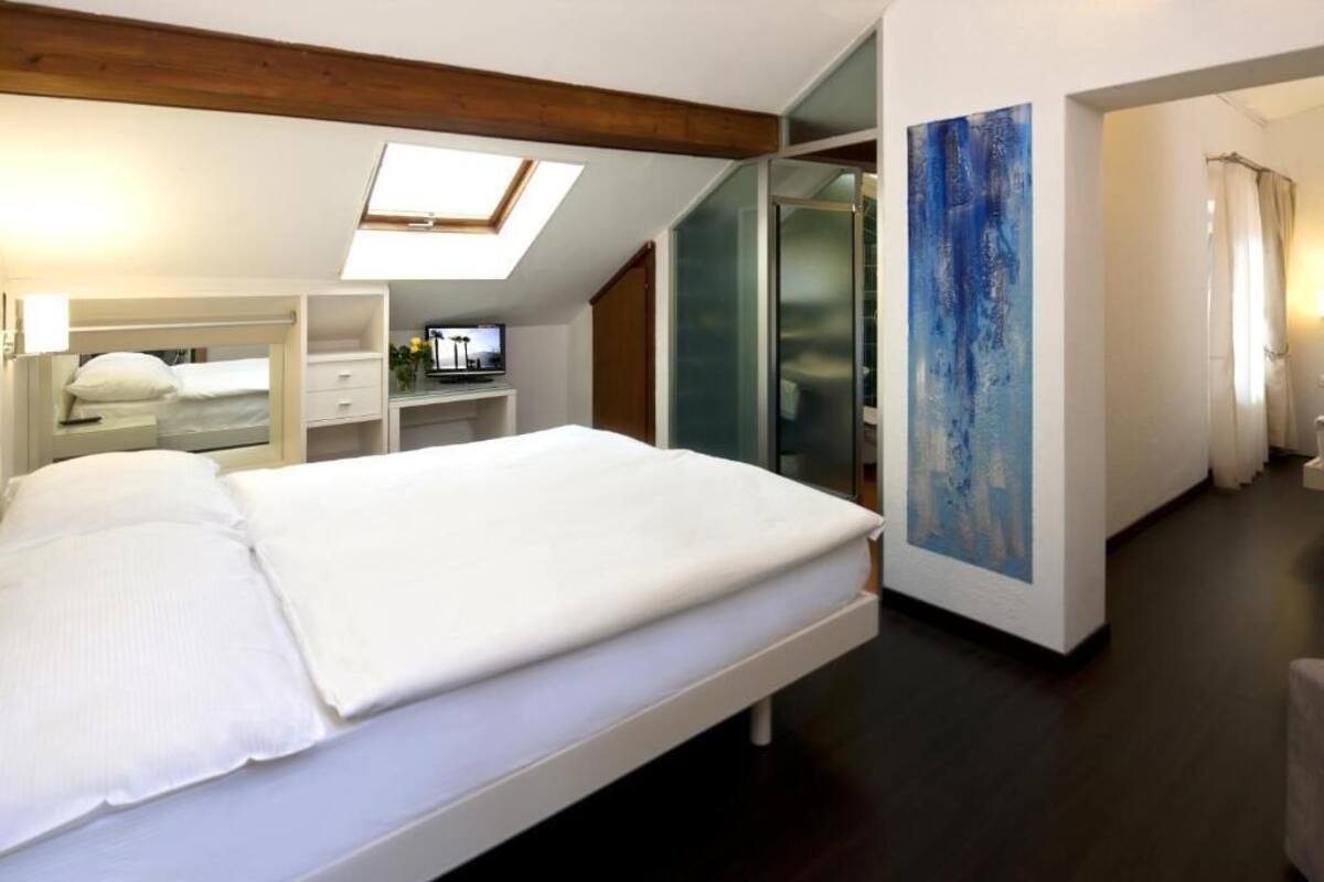 A bedroom with a bed, a TV, a painting, and a walk-in closet.