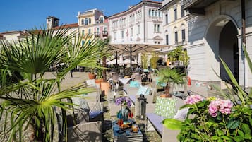 Relax in a serene outdoor space surrounded by classical architecture and lush greenery.