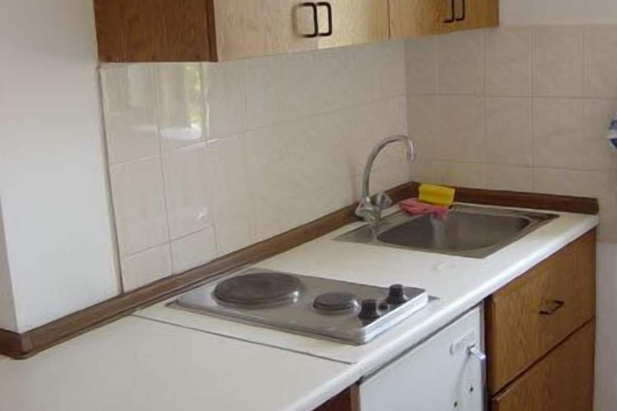 A small kitchen with white cabinets, a sink, and a white dishwasher.