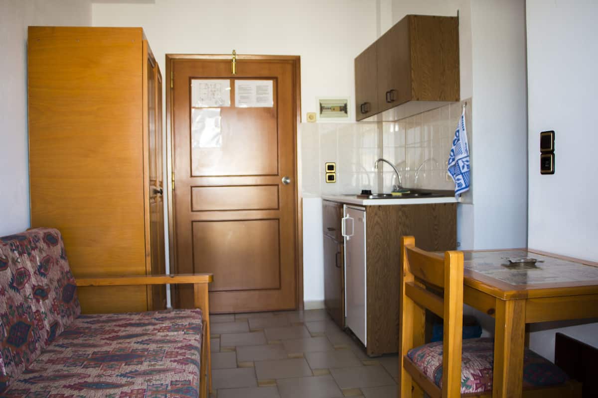 A compact kitchen with a wooden door, a small sink, and a dining table with chairs.
