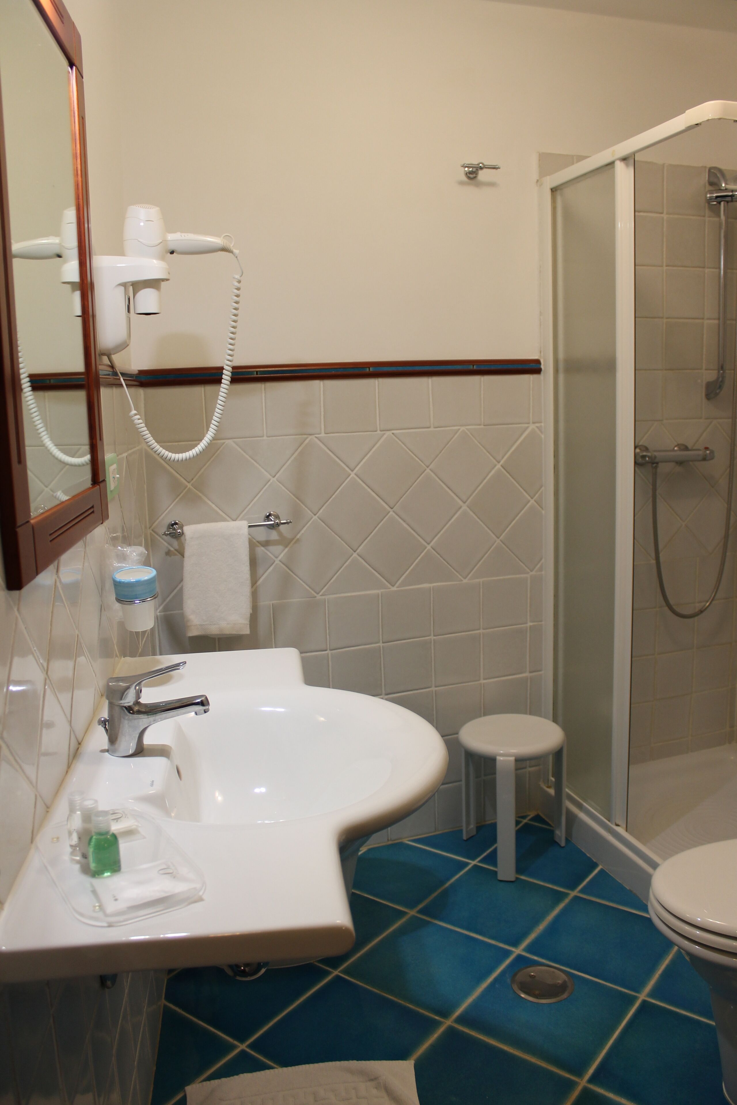 A bathroom with a sink, mirror, towel rack, and a shower area.