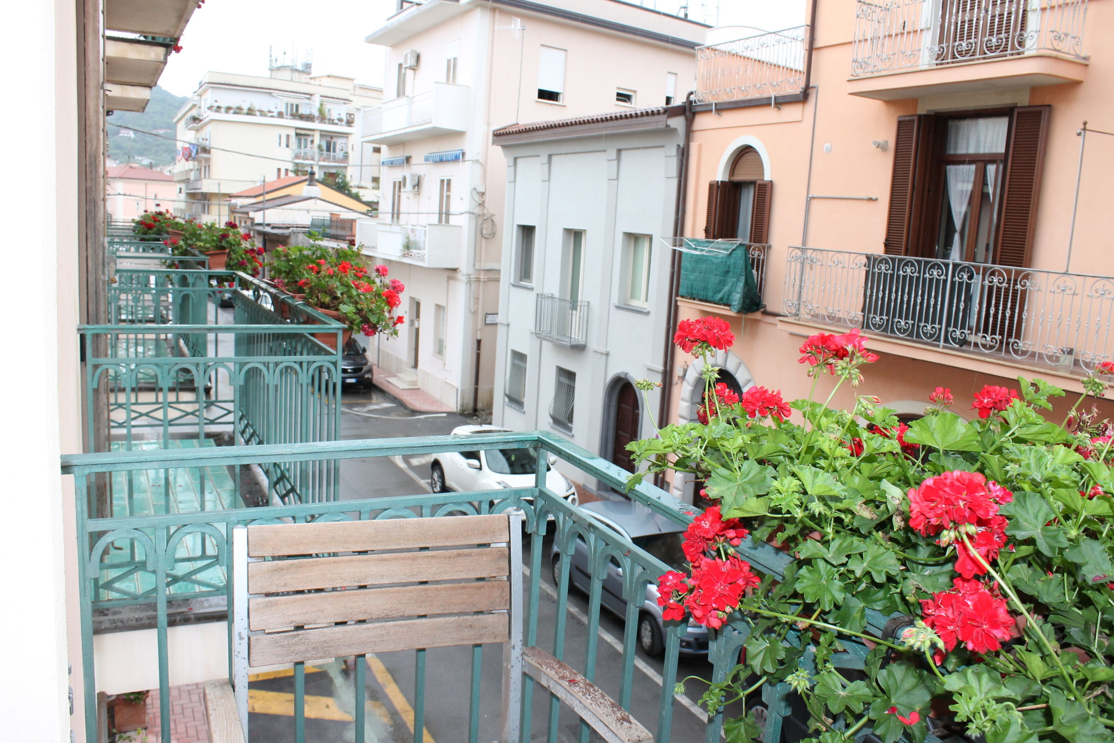 Un vicolo stretto con edifici su entrambi i lati, una panca di legno e fiori rossi in primo piano.