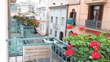 Un vicolo stretto con edifici su entrambi i lati, una panca di legno e fiori rossi in primo piano.