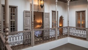 A traditional interior with wooden doors, a balcony with wrought iron railings, and a hanging lantern.