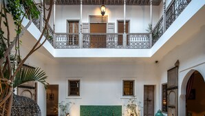 A courtyard with a pool, dining area, and a balcony with ornate railings.