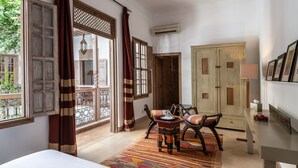 A room with a bed, a table with chairs, a wardrobe, and a window with curtains.