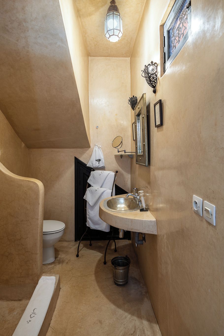 Baño compacto con inodoro, lavamanos y un pequeño cubo de basura.