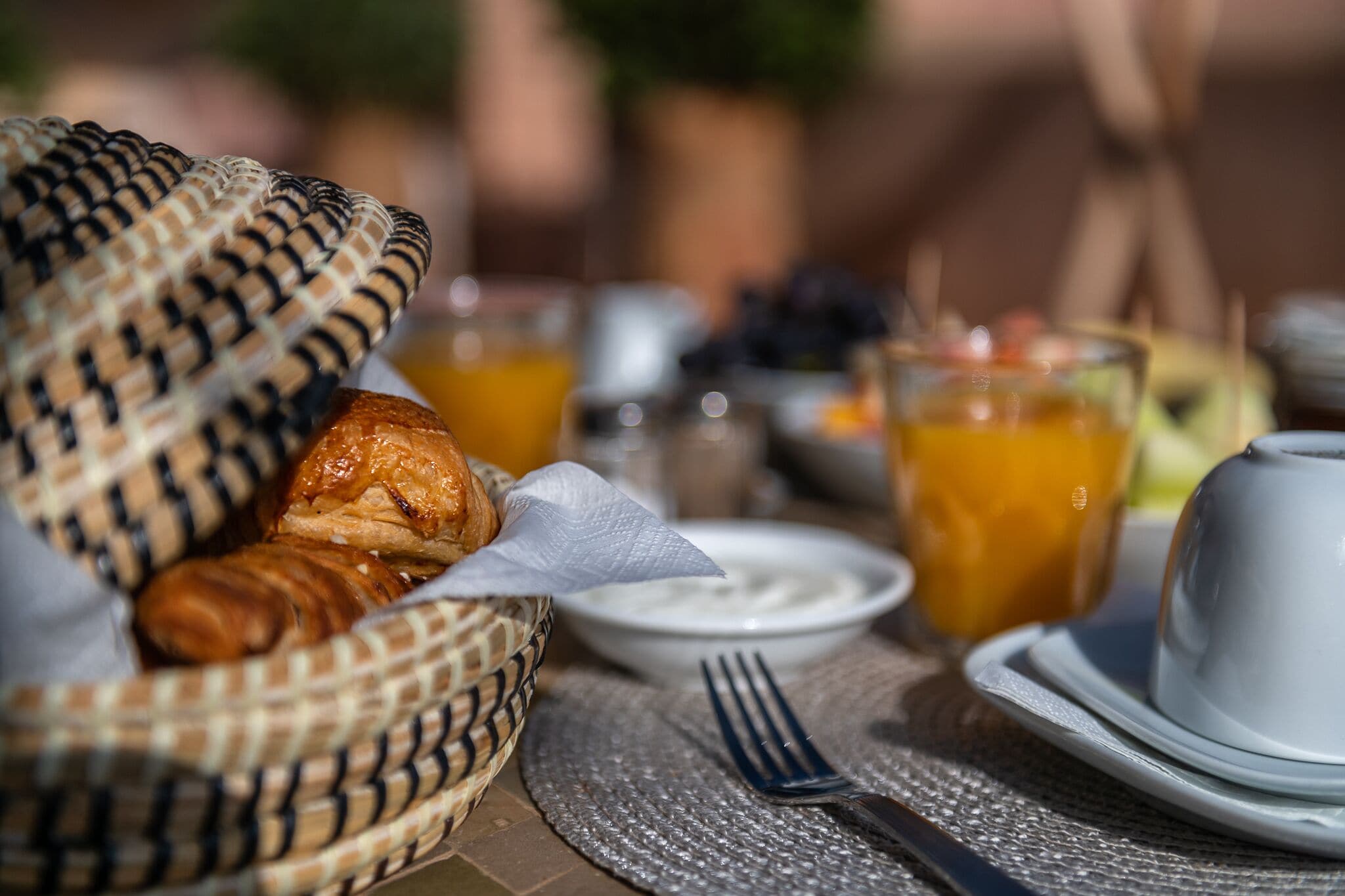 A breakfast setting with croissants, a bowl of yogurt, and glasses of orange juice.