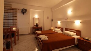 Habitació d'hotel amb dos llits, un escriptori, una cadira, una televisió i una finestra amb cortines.