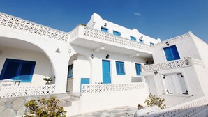 Un edificio blanco con contraventanas azules y un balcón blanco.