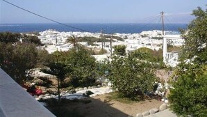 Un pueblo costero con edificios blancos, una vista despejada del mar y algo de vegetación en primer plano.