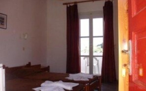 A room with a bed, a window with curtains, and a red door. - Vrissi (Mykonos)