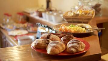 Uma mesa de buffet com diversos alimentos, incluindo doces e frutas.